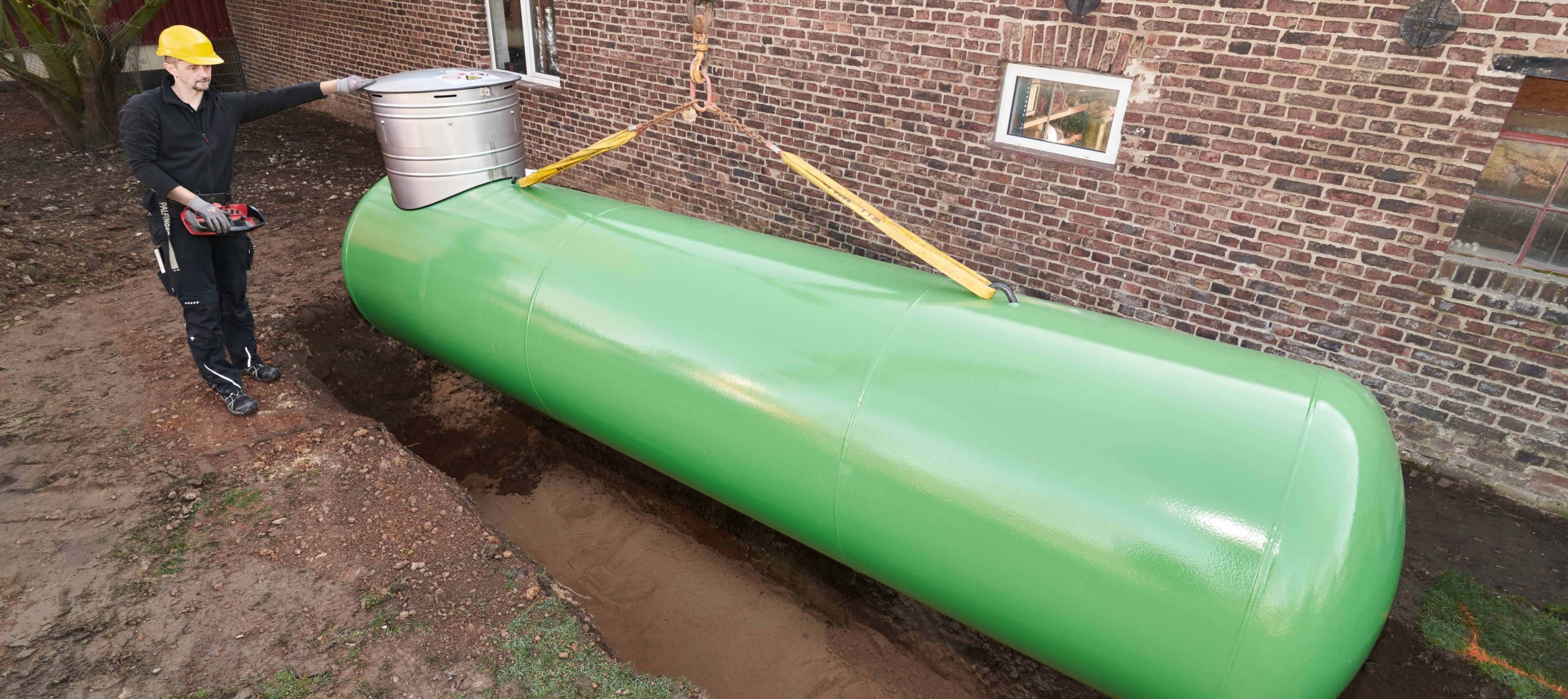 Grüner Flüssiggastank wird unterirdisch in Boden eingelassen.