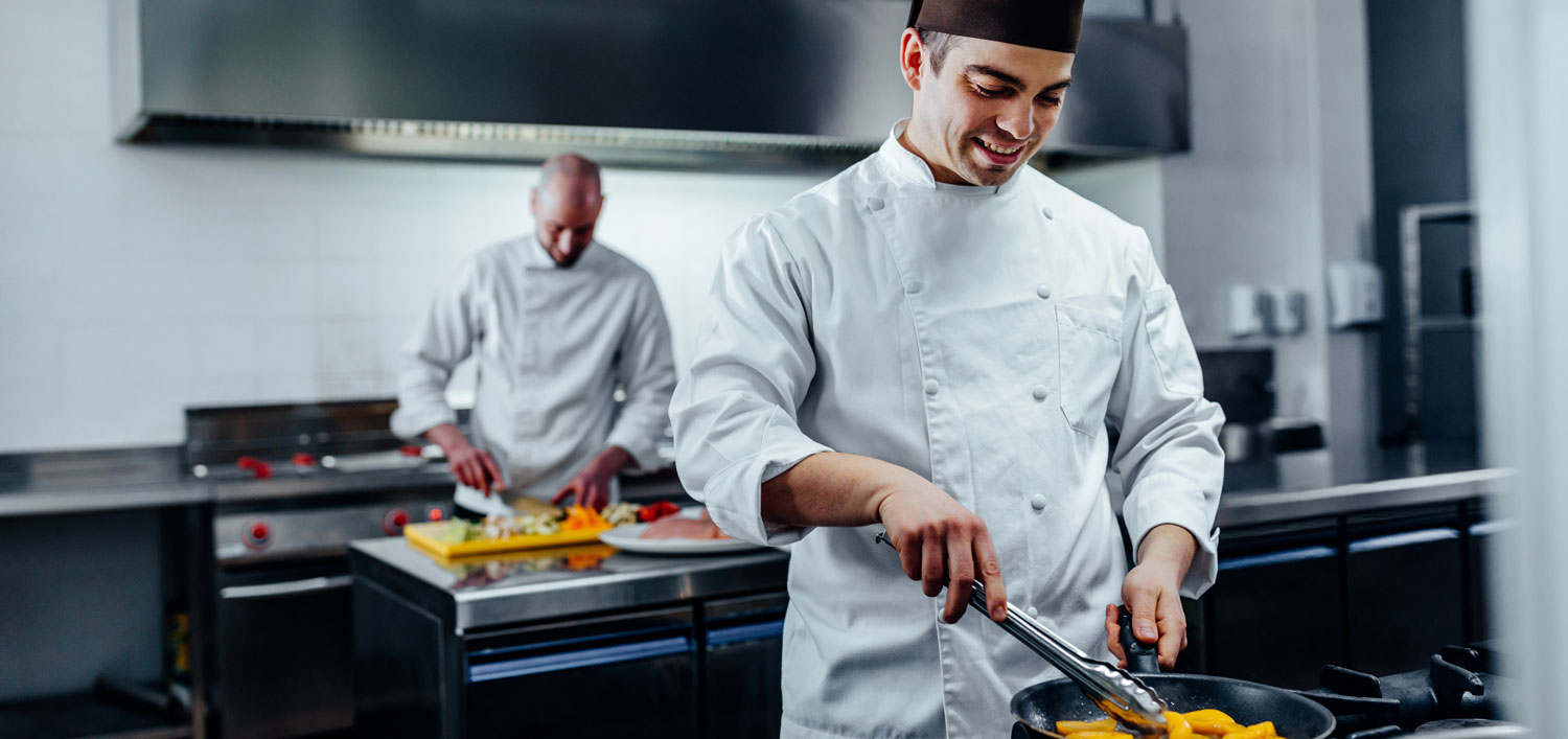 Zwei Köche in einer Profiküche bei der Zubereitung von Gerichten.