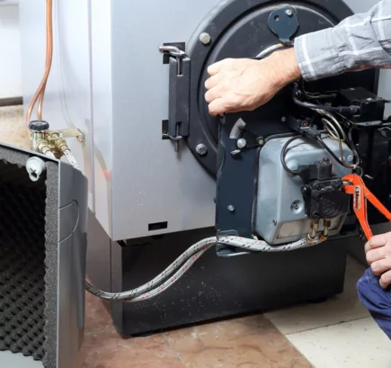 SHK-Profi, der per Zange Arbeiten an einem Heizungsbrenner ausführt.