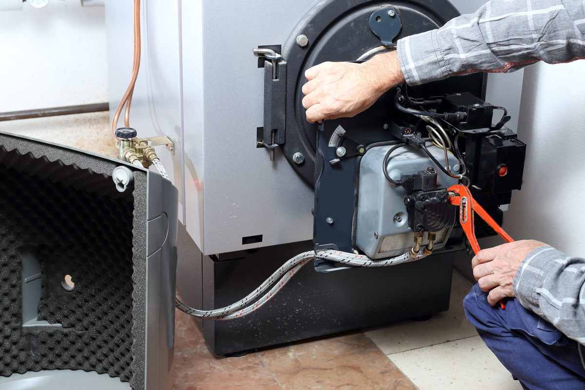 SHK-Profi, der per Zange Arbeiten an einem Heizungsbrenner ausführt.